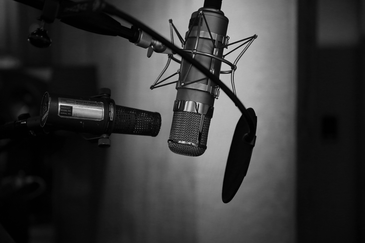 A recording studio with two cardioid microphones pointed towards a pop filter.